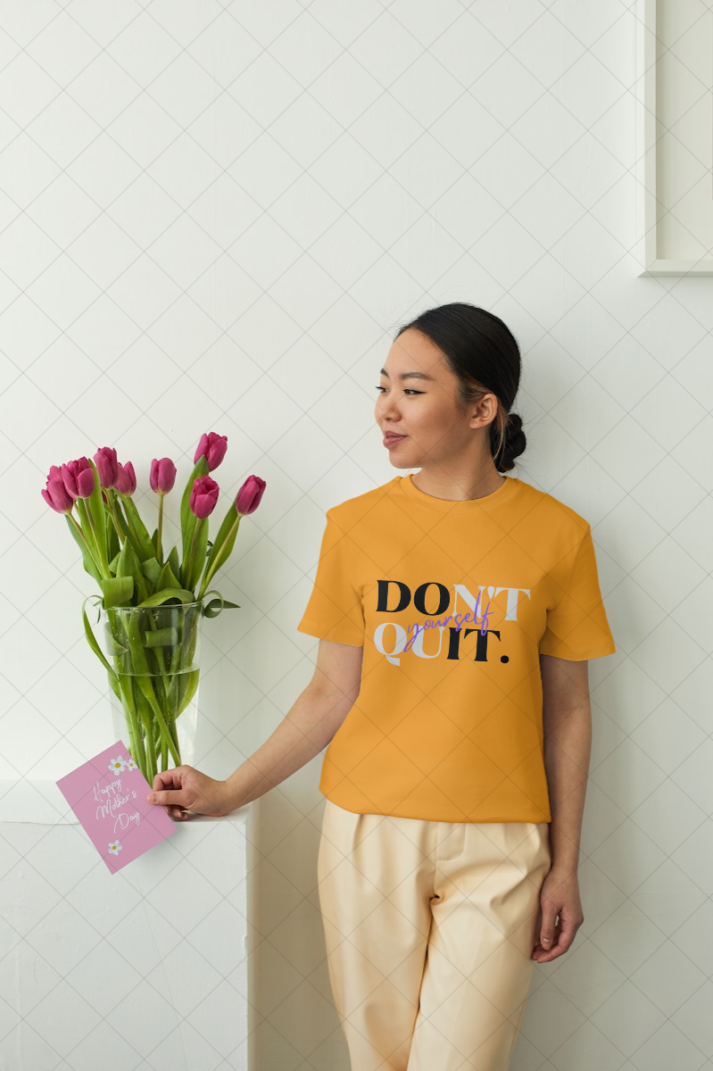 Person wearing a yellow t-shirt with 'DON'T QUIT' text, holding flowers and a card.